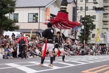 Performers toss a massive pole during the procession