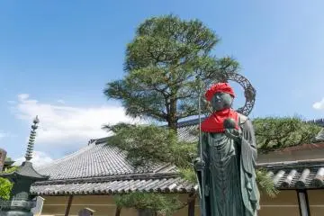 Une statue portant un château rouge et un bavoir rouge au temple Toji de Kyoto
