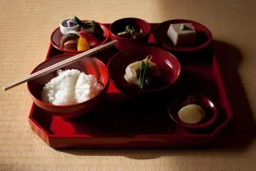 <p>L'ensemble du repas se compose de riz, soupe, l&eacute;gumes, haricots et des pr&eacute;parations de tofu vari&eacute;es, le tout servi sur un plateau de laque rouge</p>