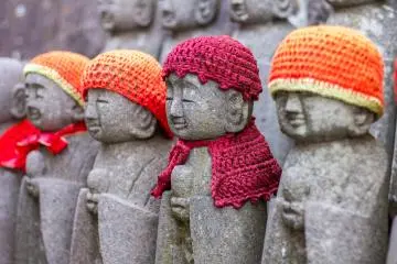 More jizo statues, whose purpose is to care for souls of unborn children and of those who die at a young age, sit in the compound, with tiny hats and capes to keep them warm
