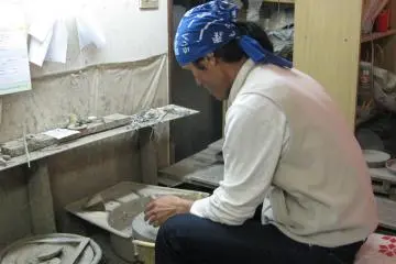 Mr. Namba sitting at his pottery wheel.