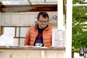 An employee stands ready to take your order at the cafe's outdoor stall