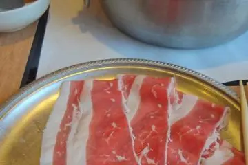 เนื้อหั่นบางๆ ต้นหอม และผักต่างๆ ปรุงให้สุกด้วยน้ำร้อน