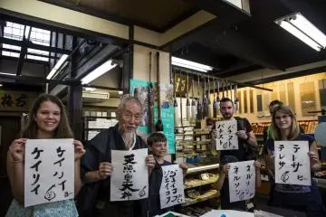 Anggota tur berpose dengan Okada setelah mereka selesai menulis nama mereka
