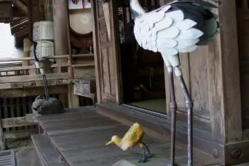 A pair of carved decorative wooden cranes and a duck