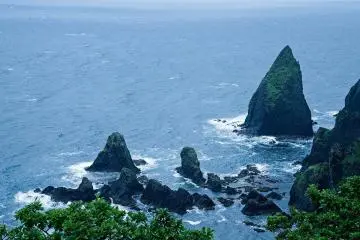 Black vertical rock formations are exposed to the wind and waves giving a sens of wilderness