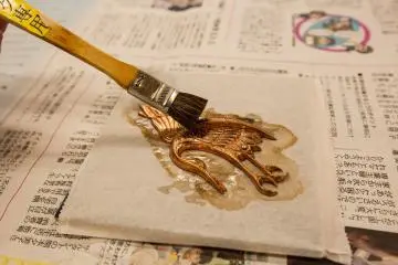 Applying glue to attach the gold leaf.