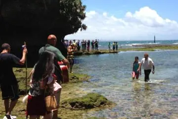 A young woman returns to the shoreline after being baptized in the waters at Toguchi Beach Park