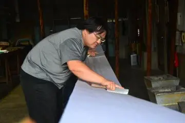 <p>Menggesek bagian belakang kain dengan pisau untuk memastikan bahwa lem beras terserap dengan sempurna.</p>