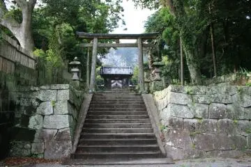 <p>green mountains behind old wooden entrance to Jusansha Shrine</p>