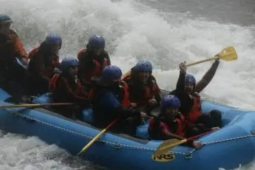 Rafting down Tone River with our champion adventurer holding his paddle up high.