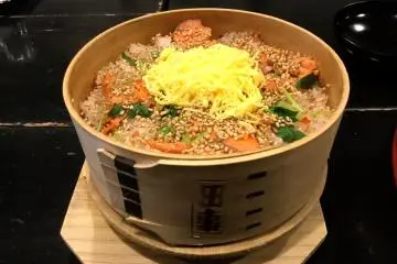 Meppameshi, rice and salmon with garnishes prepared in a bamboo 