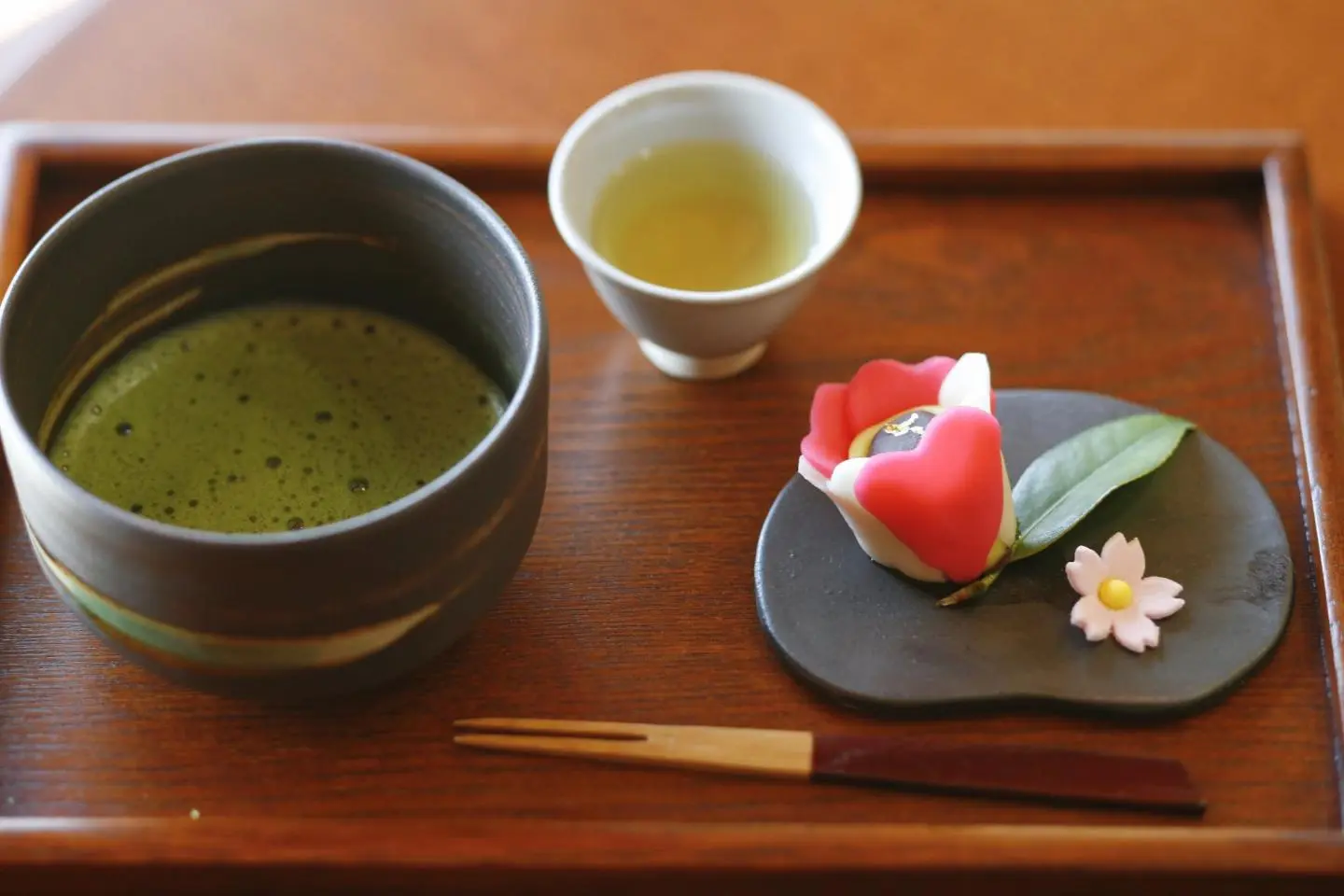 Thé vert Matcha avec une pâtisserie wagashi en forme de fleur de camélia.