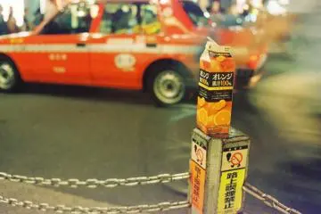 Orange juice box rests on a pole on the street of Shinjuku during the cold season.