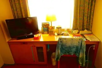 A nice long desk with a liquid crystal television, and under the desk is a foot massage machine