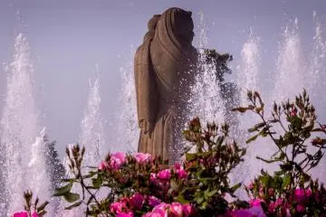 These pink roses provide a colorful foreground to this water fountain