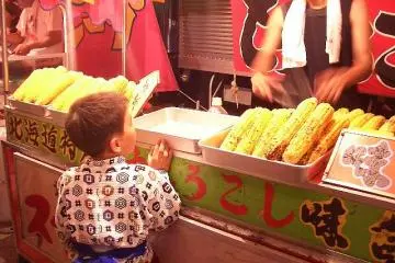 Grilled corn, a staple of the summer festival street stall scene (Photo: <a href="https://commons.wikimedia.org/wiki/File:Street_stall_-_%E7%84%BC%E3%81%8D%E3%81%A8%E3%81%86%E3%82%82%E3%82%8D%E3%81%93%E3%81%97_(28465840).jpg" target="_blank" rel="noreferrer noopener nofollow">Kanko</a> / <a href="https://creativecommons.org/licenses/by/2.0/" target="_blank" rel="noreferrer noopener nofollow">CC BY 2.0</a>)