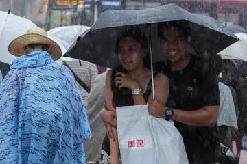 Tourists sharing an umbrella (Photo: MAHATHIR MOHD YASIN / Shutterstock.com)