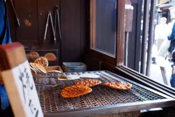 Senbei rice crackers being grilled (Photo: <a href="https://www.flickr.com/photos/kiuko/13955935599/in/photolist-74kDog-5G96rR-yBGqgk-82rAST-7HJ3yJ-ngePri-RMX1MS-cgoNF3-XEGXV1-XRAEb3-yjkteN-yBGqdV-yjktfQ-yyD34y-yjmKuQ-yjryVK-xE5gQg-yBGqh2-xE5gMR-yzZNoq-yjkt1w-yjmKmJ-yzZNtA-yyD2Sb-yjkt47-xDVZ9Y-yjksW3-yjmKts-yyD2VY-yjksWU-yjmK99-yjktbw-yjkt4h-yjkt85-yjksXA" target="_blank" rel="noreferrer noopener nofollow">きうこ</a> / <a href="https://creativecommons.org/licenses/by-nd/2.0/" target="_blank" rel="noreferrer noopener nofollow">CC BY-ND 2.0</a>)