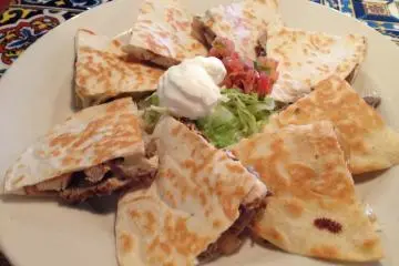 Steak and Chicken fajita quesadillas topped with sour cream, lettuce and salsa Mexicana
