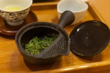 Kyusu (teko tradisional Jepang) mengkilap dan bekas daun teh yang sudah diseduh