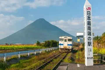 Blue sky and Kaimondake in the background as a train approaches