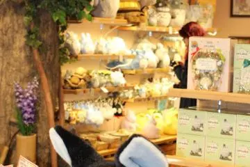 Jiji from Kiki's Delivery service, with a wall of Totoro plush toys in the background