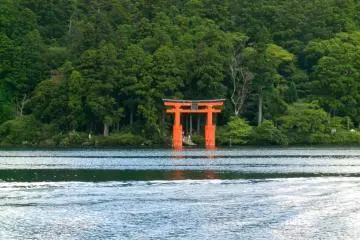 The red torii stands out among the tree as you cruise across the lake.