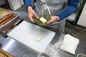 Put the topping on a persimmon leave, then add the rice and wrap all up. 