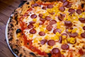 Stone oven cooked pizza with sausage and corn at La Bière pizzeria