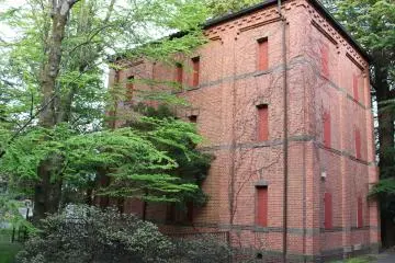 The former library stack for Japan’s Second Senior High School hides in a dark corner of the courtyard behind trees.