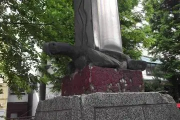 A hardy turtle supports a pillar in the parking lot by the entrance