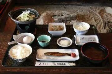 Breakfast Menu, starting from the top left - Simmered miso shellfish, stewed butterbur, chinese yam, raw egg (to be poured into the shellfish), kombu, pickled vegetables, flavoured seaweed (nori), rice, sweet boiled rainbow trout, kenojiru (a traditional Tsugaru soup).