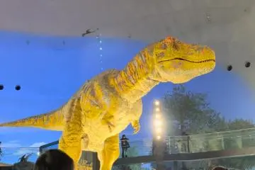 A T-Rex animatronic sits in the middle of an exhibition hall, roaring at the visitors passing by