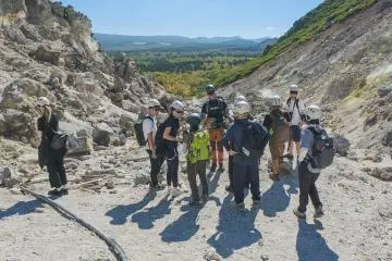 Hagi, wearing the blue helmet at the back of the image, explains to the tour group about the geology of Mt. Io.