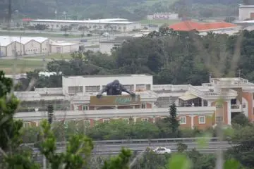 <p>Overgrown trees and nearby power lines obstruct part of the 360 degree view from the observation tower. This view to the west shows the Hotel Royal III love hotel and the Okinawa Expressway with the Camp Shields American Navy Base in the background</p>