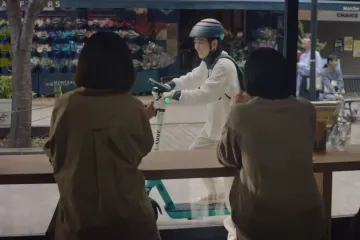 Two people looking out the window of a cafe, seeing someone glide by on a LUUP scooter