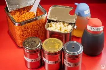 (Top row from left) spicy tenkasu tempura bits, garlic, vinegar, “punch sauce,” (bottom row from left), black pepper, curry power, special chili powder