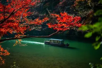 Picture-perfect Arashiyama in Autumn (Photo: <a href="https://unsplash.com/photos/a-boat-traveling-down-a-river-surrounded-by-trees-kjsSHDpQfBo" target="_blank" rel="noreferrer noopener nofollow">Nicolas Caetano</a> / Unsplash)