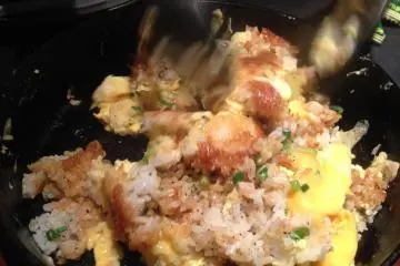 <p>Stir your garlic fried rice to mix up the eggs, onions and rice together</p>