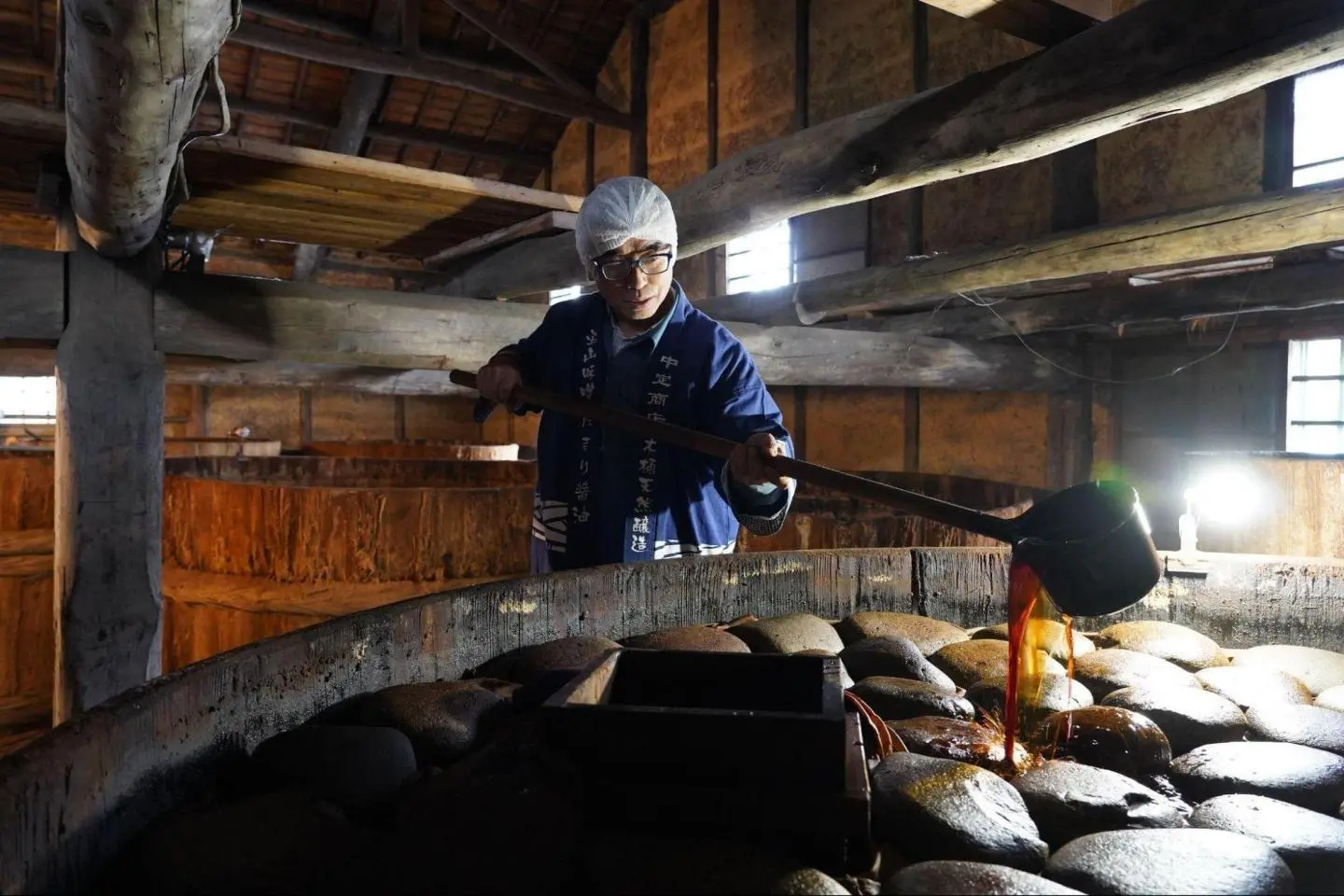Pouring soy sauce back into the wooden vat