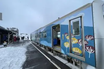 Passengers disembark at a windswept station