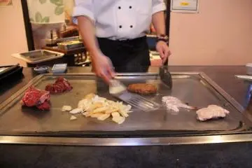 Koki teppanyaki terbaik yang sedang menyiapkan beberapa makanan pesanan Anda pada saat yang bersamaan, dimana di tempat lain akan memasaknya secara terpisah.