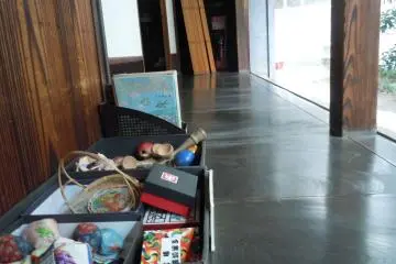 <p>Several antique origami instruction books and toys are put out in a box on the open covered porch facing the&nbsp;courtyard/garden.&nbsp;</p>
