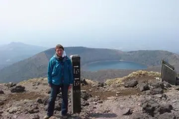 The author on one peak of the Kirishima range with a crater lake in the background
