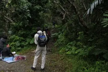<p>A village official speaks to an Okinawan who was praying at the beginning of a trail that leads to a handful of shrines and several&nbsp;mountain peaks near the village office</p>