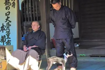 Temple monks and their dog, observing the market.