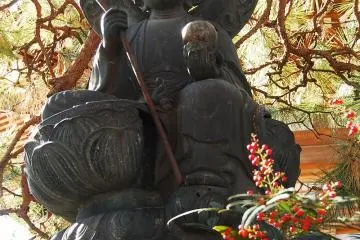 <p>รูปปั้นพระพุทธองค์ใต้ร่มเงาต้นสนใหญ่</p>