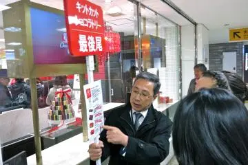 Un membre du personnel de la chocolaterie KitKat tient une pancarte indiquant la fin de la file d'attente et les saveurs disponibles