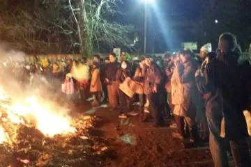 <p>Spectators warm themselves in the chilly night.&nbsp;</p>